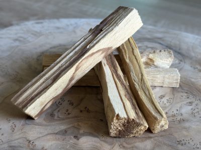 Bâtonnet de Palo Santo naturel posé sur un fond en bois, sélectionné par Akasha Énergies.
